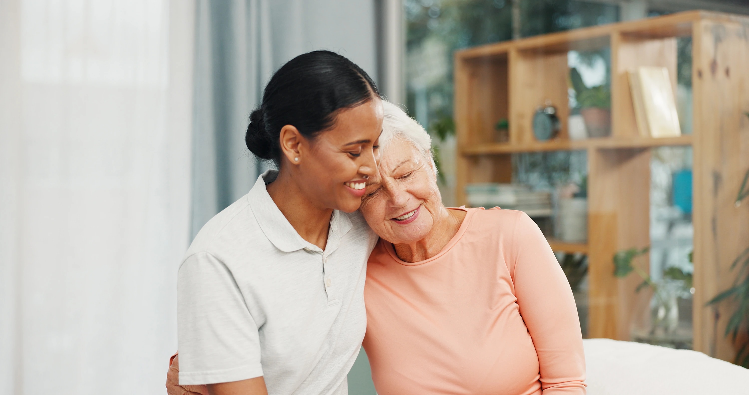 A caregiver and an older woman sharing a quiet moment together at home.